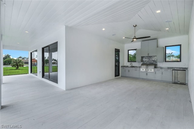 unfurnished living room with lofted ceiling, sink, wood ceiling, light wood-type flooring, and ceiling fan