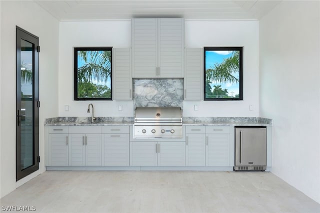 kitchen with fridge, light stone counters, sink, and plenty of natural light