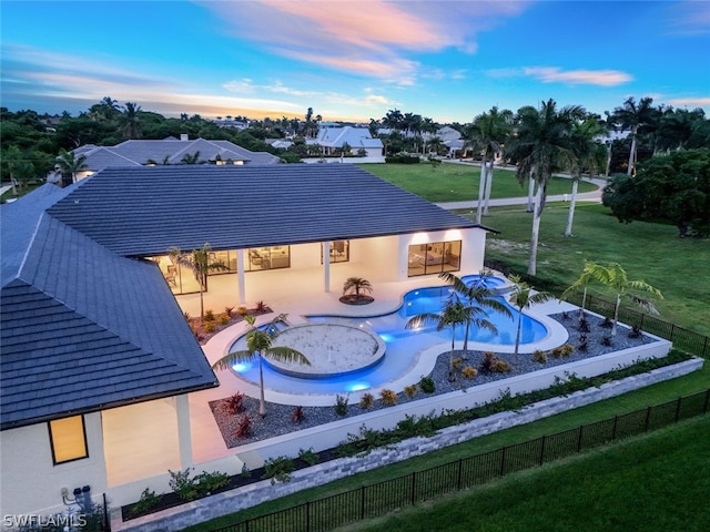 pool at dusk featuring a yard and a patio area