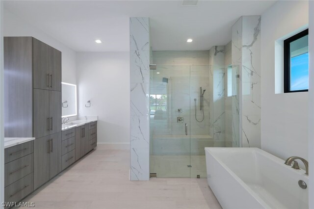 bathroom with separate shower and tub, hardwood / wood-style floors, and vanity