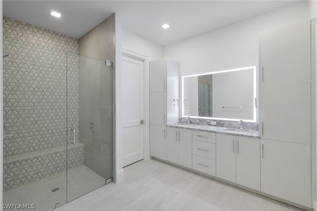 bathroom with dual vanity and an enclosed shower