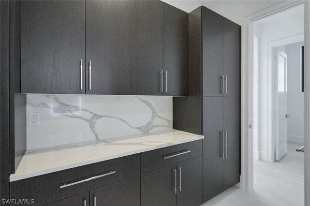 kitchen featuring light stone counters and dark brown cabinets