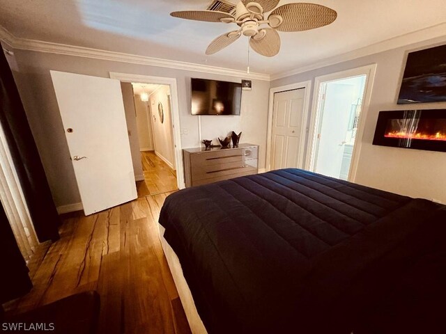 bedroom featuring a closet, hardwood / wood-style flooring, ceiling fan, ensuite bath, and ornamental molding