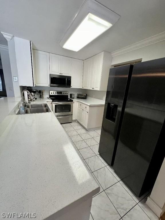 kitchen with stainless steel electric stove, light countertops, white cabinets, a sink, and black fridge