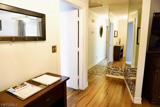 hall with ornamental molding, light wood-style flooring, and baseboards