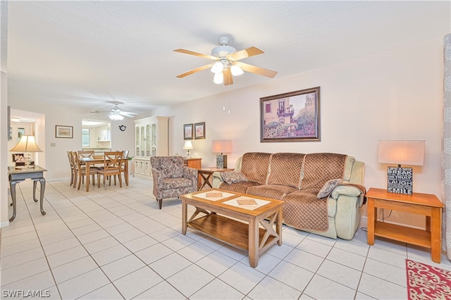 living room featuring ceiling fan, light tile patterned floors, and a textured ceiling