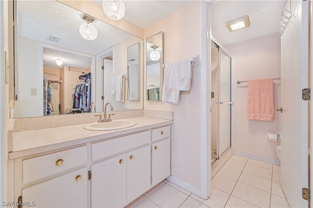 bathroom with tile patterned flooring, vanity, a shower with door, and a textured ceiling