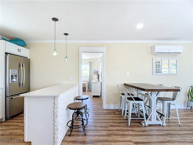 kitchen featuring stainless steel fridge with ice dispenser, light hardwood / wood-style flooring, an AC wall unit, and a healthy amount of sunlight