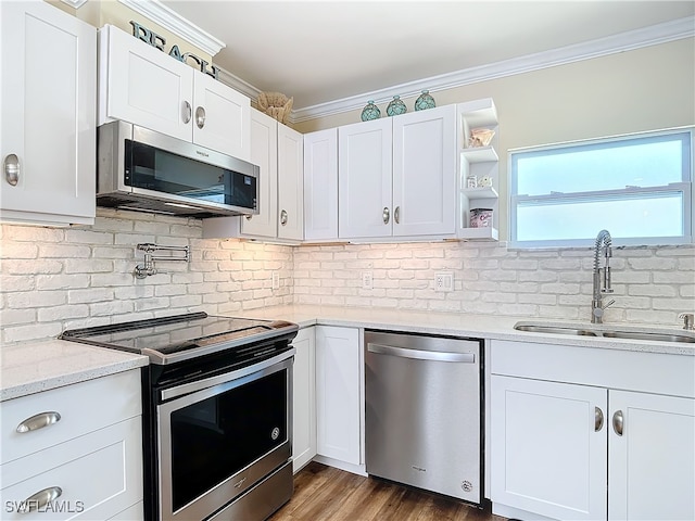 kitchen featuring stainless steel appliances, decorative backsplash, sink, white cabinets, and hardwood / wood-style flooring