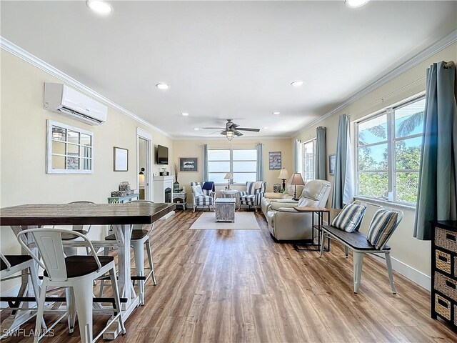 living room featuring light wood-type flooring, ornamental molding, ceiling fan, and an AC wall unit