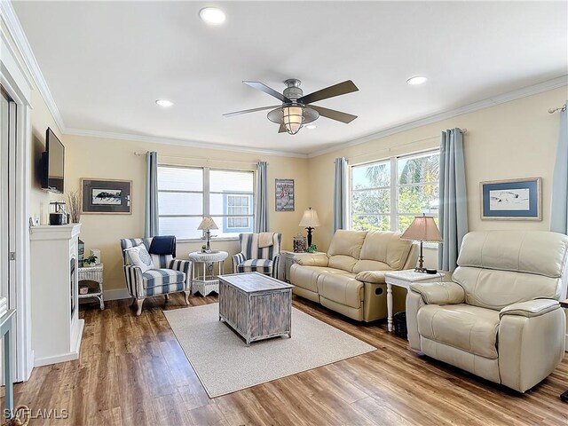 living room featuring hardwood / wood-style flooring, plenty of natural light, crown molding, and ceiling fan