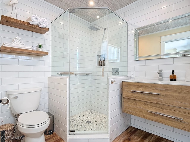 bathroom with wood-type flooring, toilet, vanity, and tile walls