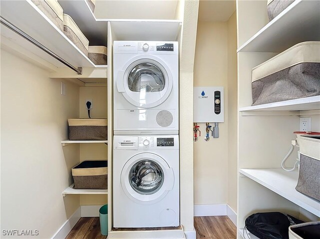 clothes washing area featuring stacked washer and clothes dryer and wood-type flooring