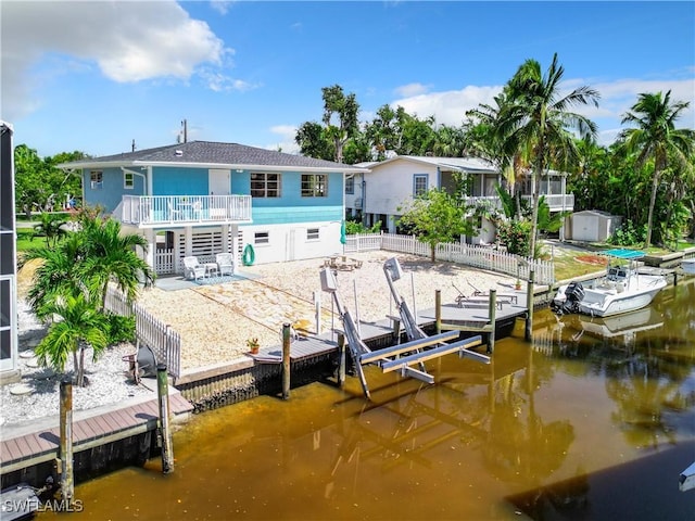 view of dock with stairway, a fenced backyard, a water view, and boat lift