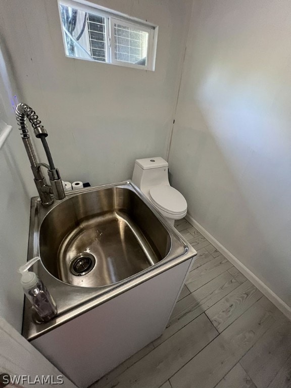 bathroom featuring hardwood / wood-style flooring, a bath, and toilet