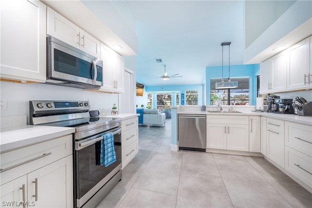 kitchen with stainless steel appliances, sink, white cabinets, ceiling fan, and hanging light fixtures