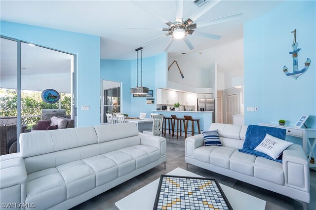 living room featuring ceiling fan, vaulted ceiling, and concrete flooring