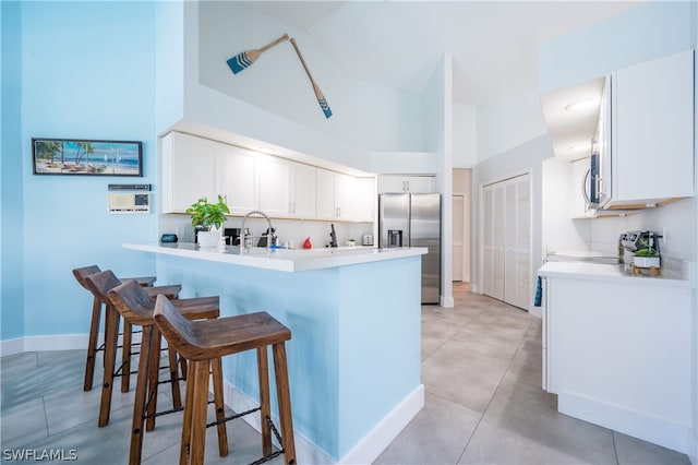 kitchen with stainless steel appliances, white cabinets, a kitchen bar, and kitchen peninsula