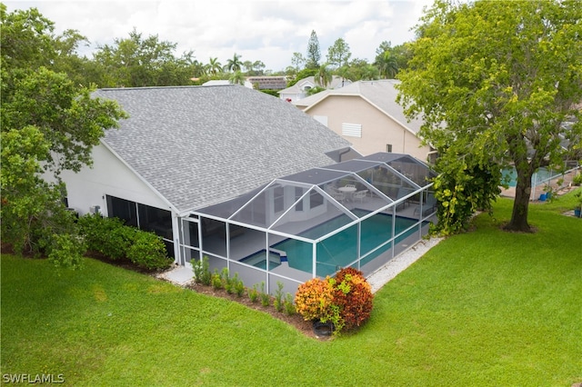 rear view of house with glass enclosure and a lawn