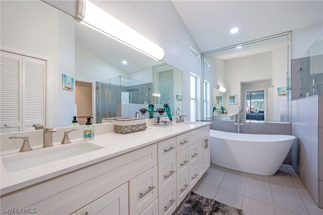 bathroom with lofted ceiling, vanity, tile patterned flooring, and independent shower and bath