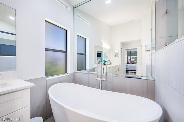 bathroom with tile walls, a tub, and vanity