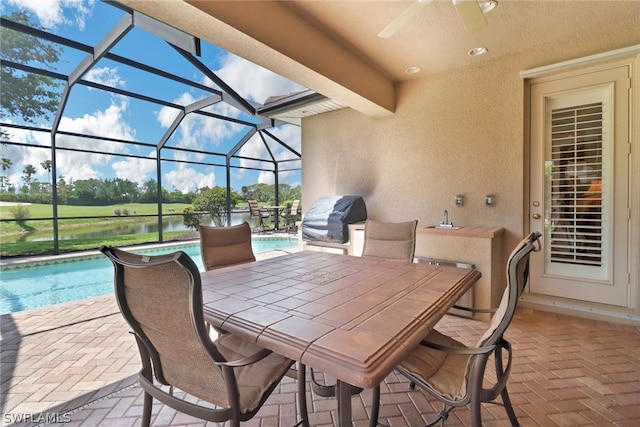 view of patio with a water view, a grill, sink, and a lanai