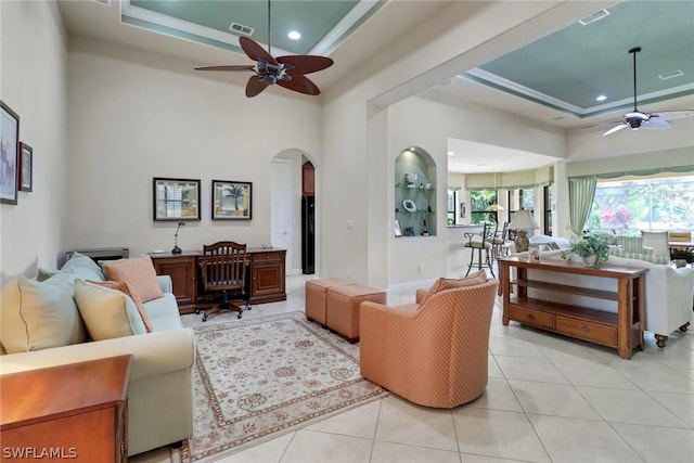 living room featuring light tile patterned floors, a tray ceiling, ceiling fan, and a high ceiling