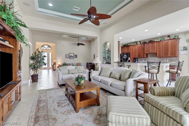 living room with a raised ceiling, light tile patterned floors, and ceiling fan