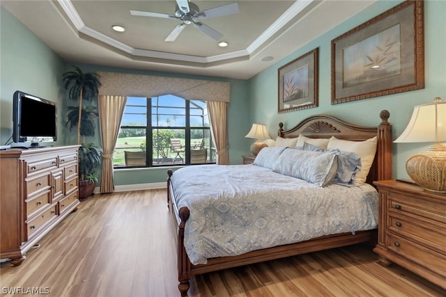 bedroom featuring crown molding, light hardwood / wood-style flooring, and a raised ceiling