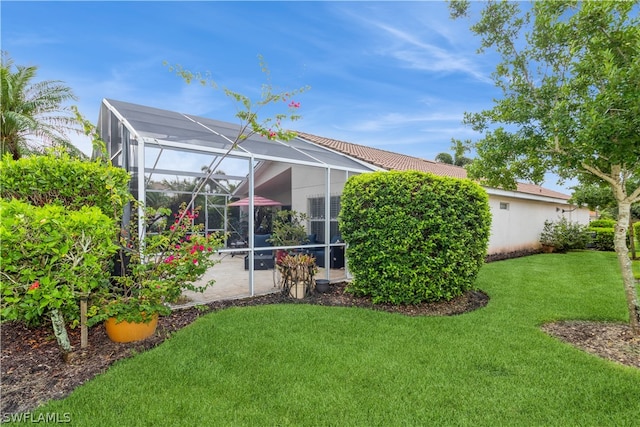 rear view of property with a patio, a yard, and a lanai