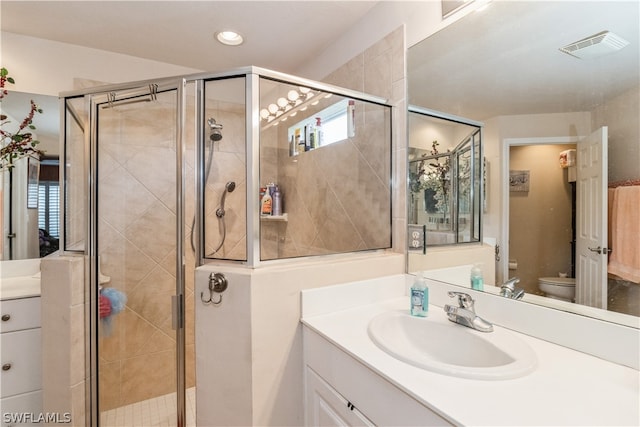 bathroom featuring a shower with door, toilet, and vanity