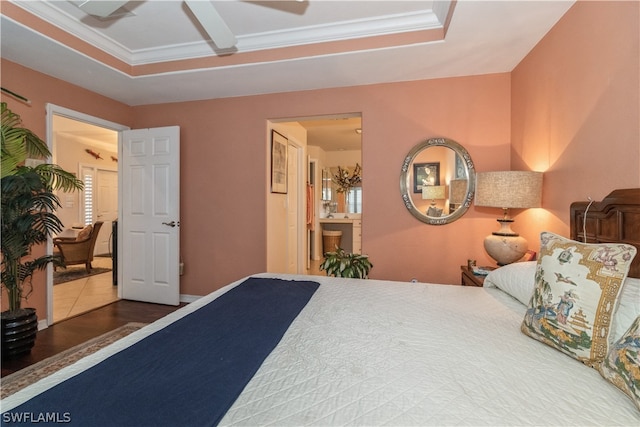 bedroom with a tray ceiling, hardwood / wood-style floors, ensuite bath, and ceiling fan