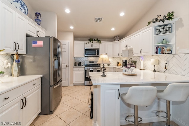 kitchen featuring white cabinets, stainless steel appliances, tasteful backsplash, and kitchen peninsula