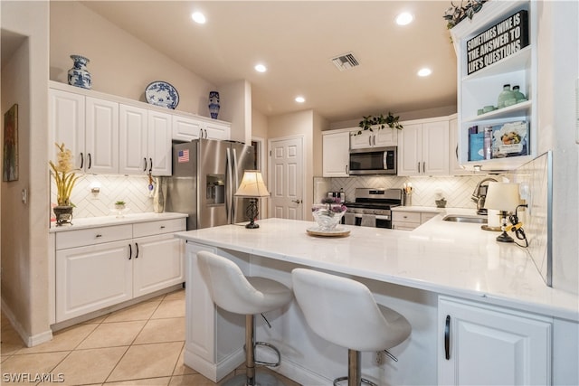 kitchen with white cabinetry, stainless steel appliances, light tile patterned flooring, and tasteful backsplash