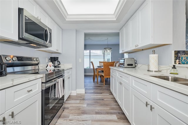 16580 Waters Edge Ct Unit 102, Fort Myers, FL 33908 - kitchen featuring ornamental molding, a raised ceiling, light wood finished floors, white cabinets, and appliances with stainless steel finishes