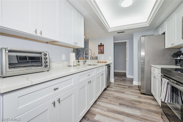 kitchen with stainless steel appliances, sink, light stone counters, light hardwood / wood-style floors, and white cabinetry