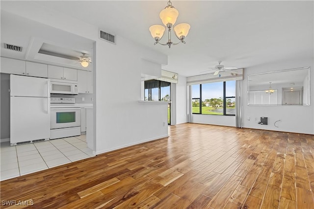 unfurnished living room featuring ceiling fan with notable chandelier and light hardwood / wood-style floors