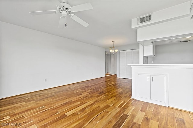 unfurnished living room with ceiling fan with notable chandelier and light wood-type flooring