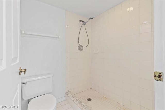 bathroom with tile patterned floors, a tile shower, and toilet