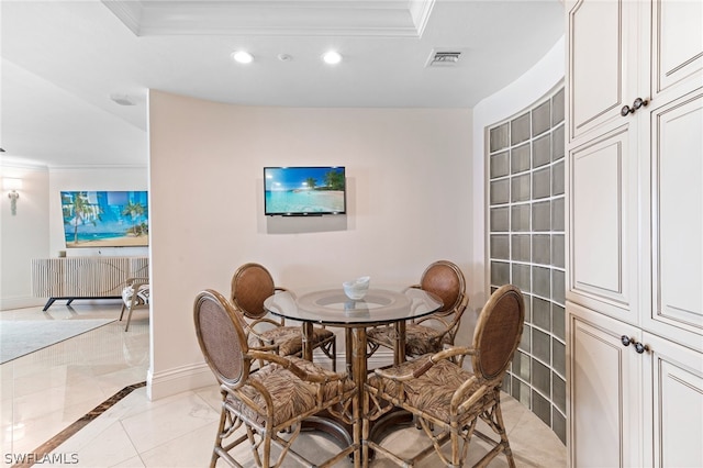 dining room with crown molding, a tray ceiling, and light tile patterned floors