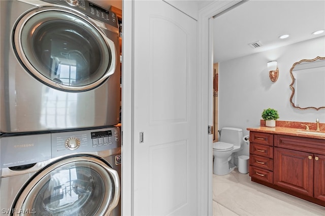 washroom featuring stacked washer and dryer, sink, and light tile patterned floors