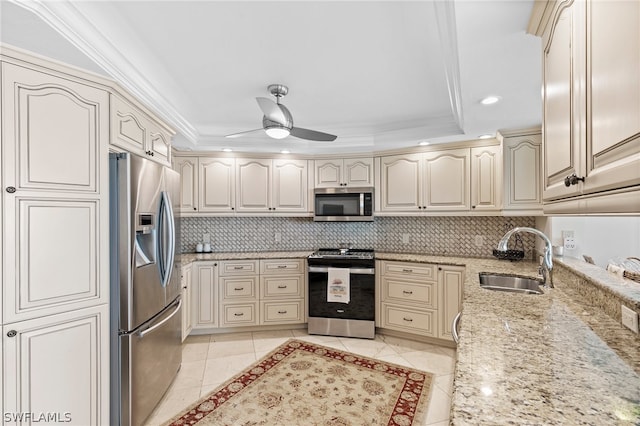 kitchen with appliances with stainless steel finishes, sink, decorative backsplash, ceiling fan, and a raised ceiling