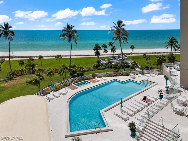 view of pool featuring a water view, a patio, and a view of the beach