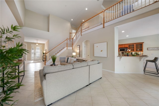 living room with light tile patterned flooring and a towering ceiling