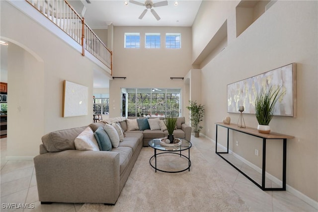 living room featuring ceiling fan, light tile patterned floors, a high ceiling, and a wealth of natural light