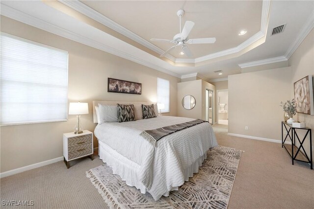 carpeted bedroom featuring multiple windows, ornamental molding, connected bathroom, and a tray ceiling