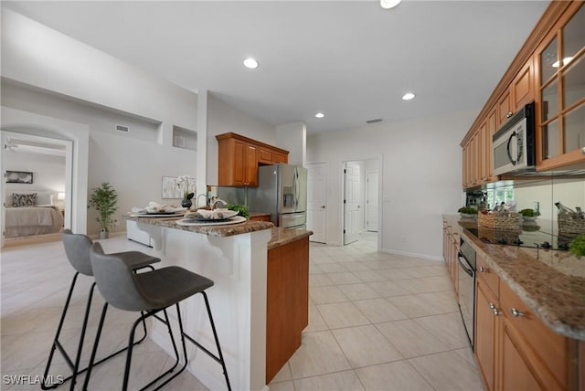 kitchen featuring light stone counters, stainless steel appliances, kitchen peninsula, and a breakfast bar area