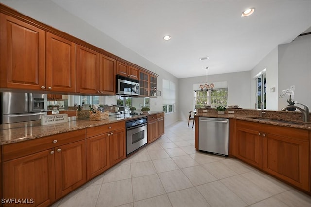 kitchen with sink, an inviting chandelier, stainless steel appliances, decorative light fixtures, and dark stone counters