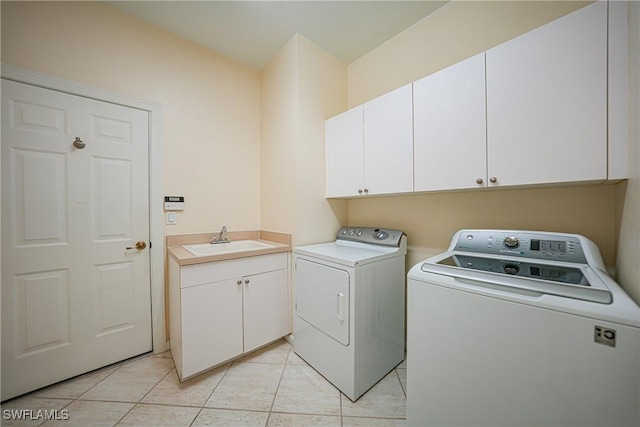 clothes washing area with cabinets, washing machine and dryer, sink, and light tile patterned floors