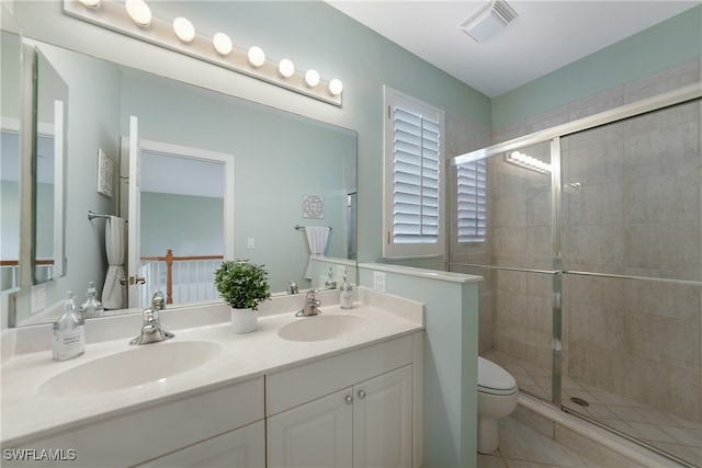 bathroom featuring a shower with door, tile patterned flooring, toilet, and double sink vanity